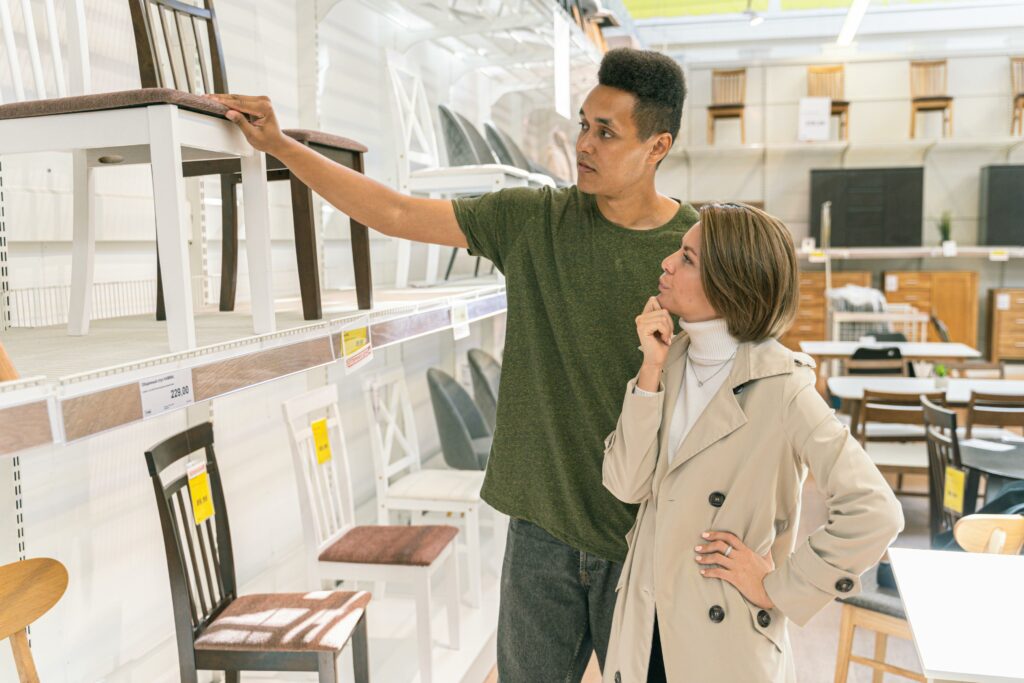 A couple examining chairs in a well-lit furniture store aisle.